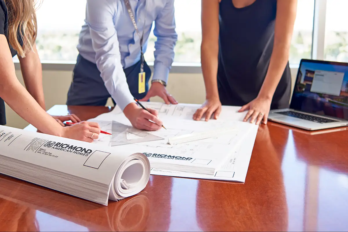 Employees talking over architectural drawings on a table